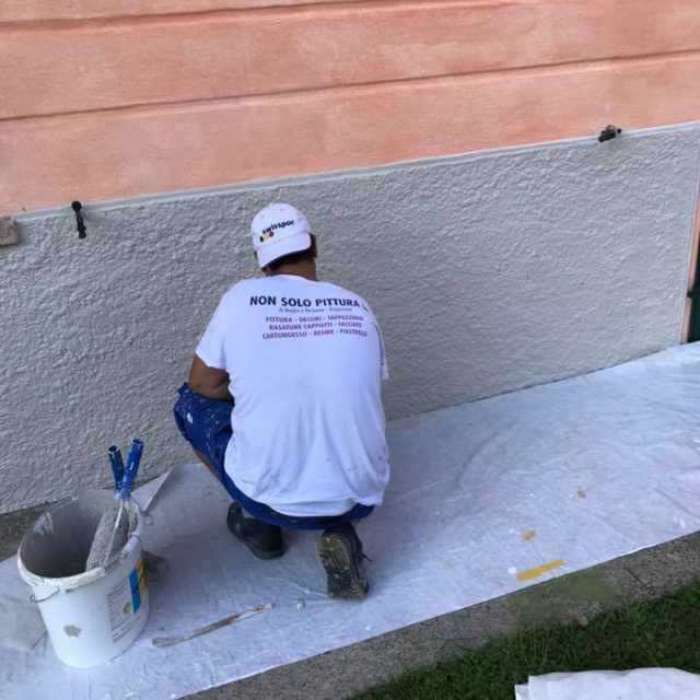 un muratore esegue delle ristrutturazioni su una parete esterna ad una casa